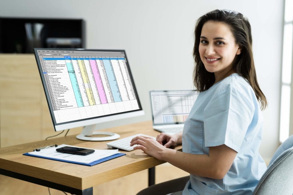 woman in scrubs in front of computer